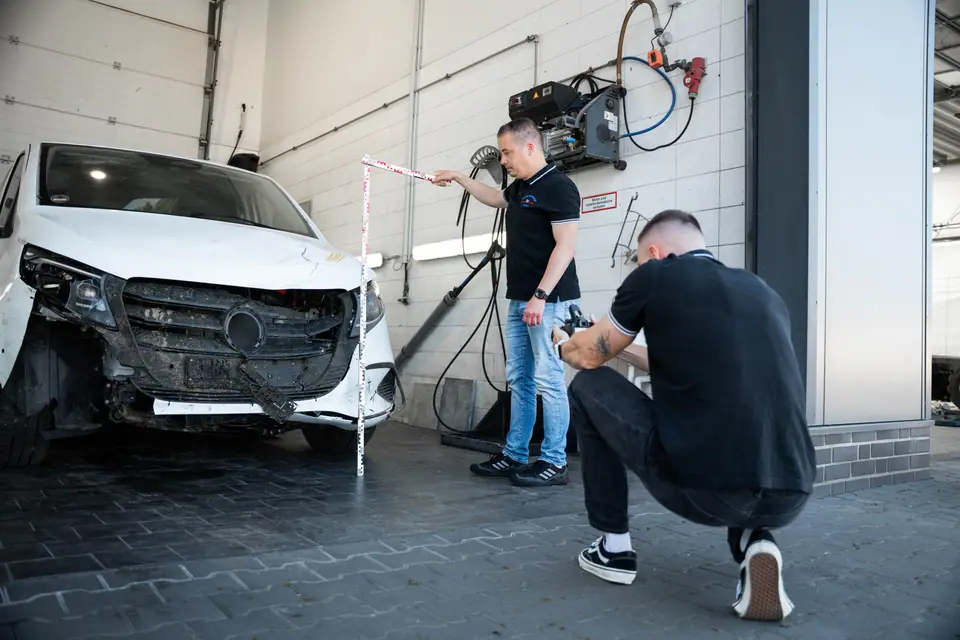 Zwei Kfz-Sachverständige von Knoche & Vendt vermessen und fotografieren einen Unfallschaden an einem Transporter