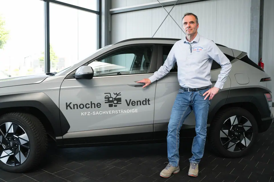 Kfz-Sachverständiger von Knoche & Vendt neben dem Firmenfahrzeug