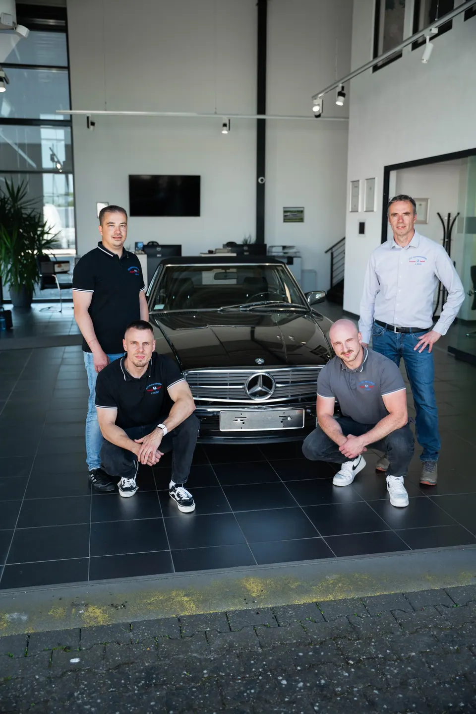 Teamfoto von Knoche & Vendt vor einem Mercedes-Fahrzeug in der Werkstatt
